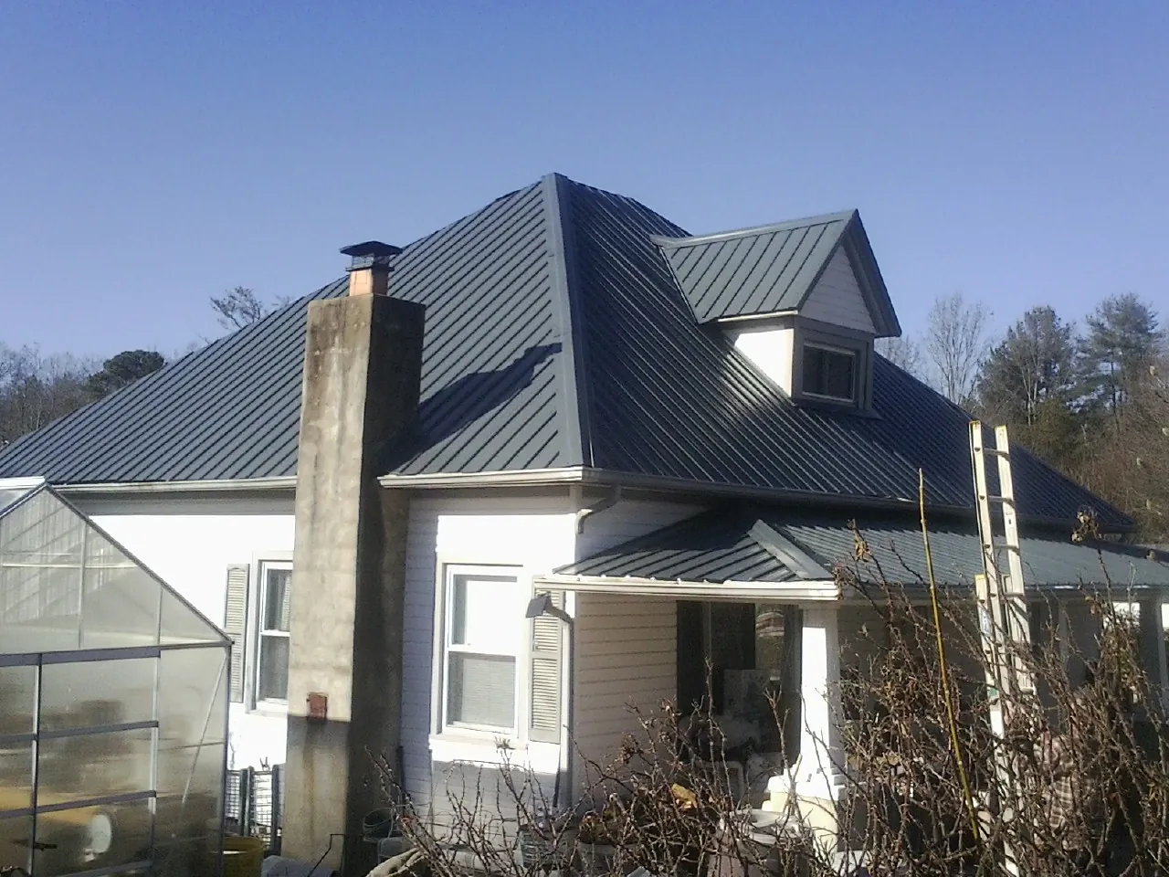 Dark blue standing seam metal roof on a white farmhouse with dormer — Slate & Tile Roof Repair by Roofing Brothers in Shady Side