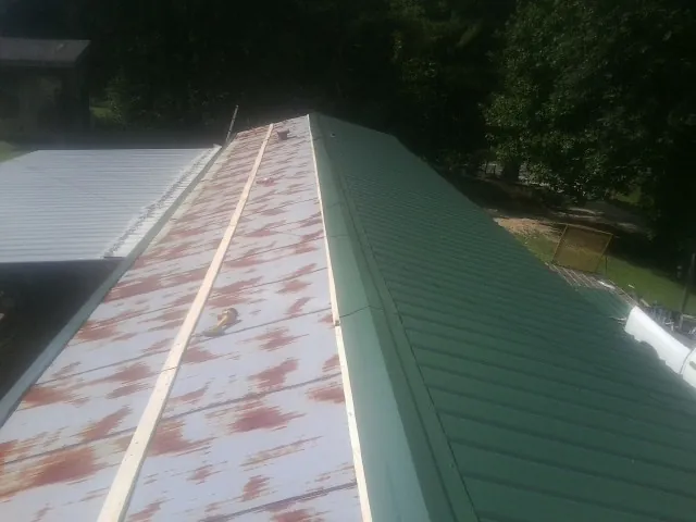 Old rusted panels beside newly installed green metal roofing — Wind Damage Roof Repair by Roofing Brothers in Shady Side