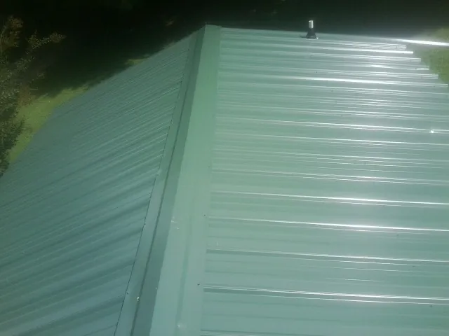 New green metal panels meeting at the ridge of a roof — Flat Roof Repair work by our crew in Shady Side