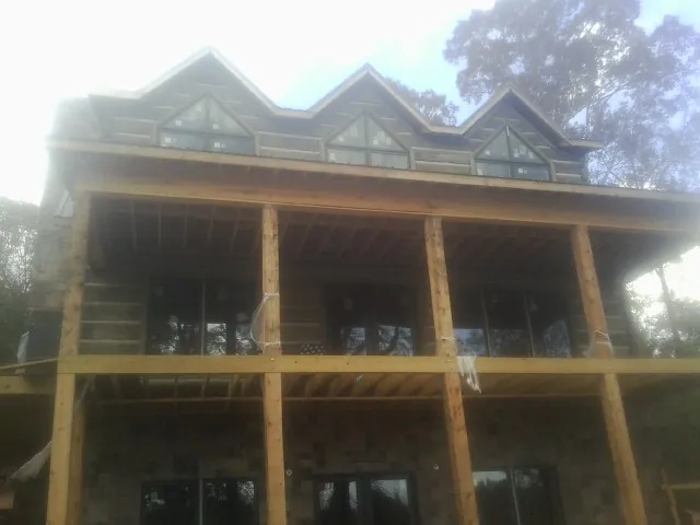 Dormers and porch framing on a large log home under construction — Roof Coating work by our crew in Shady Side