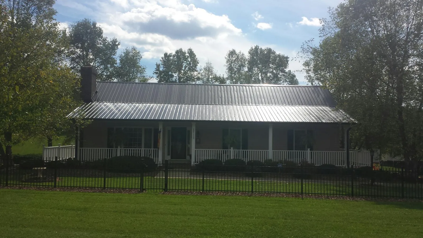Gray metal roof on a brick ranch with a full width front porch — Gutter Guard Installation work by our crew in Shady Side
