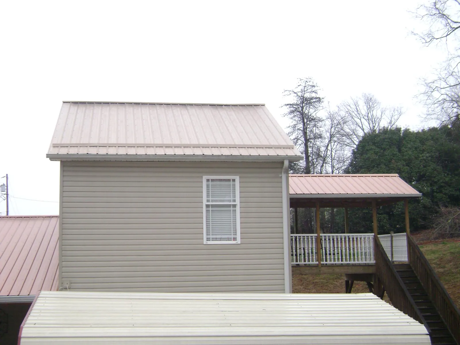 Tan metal roofs on a two story addition and attached porch, from a Roof Replacement job in Shady Side